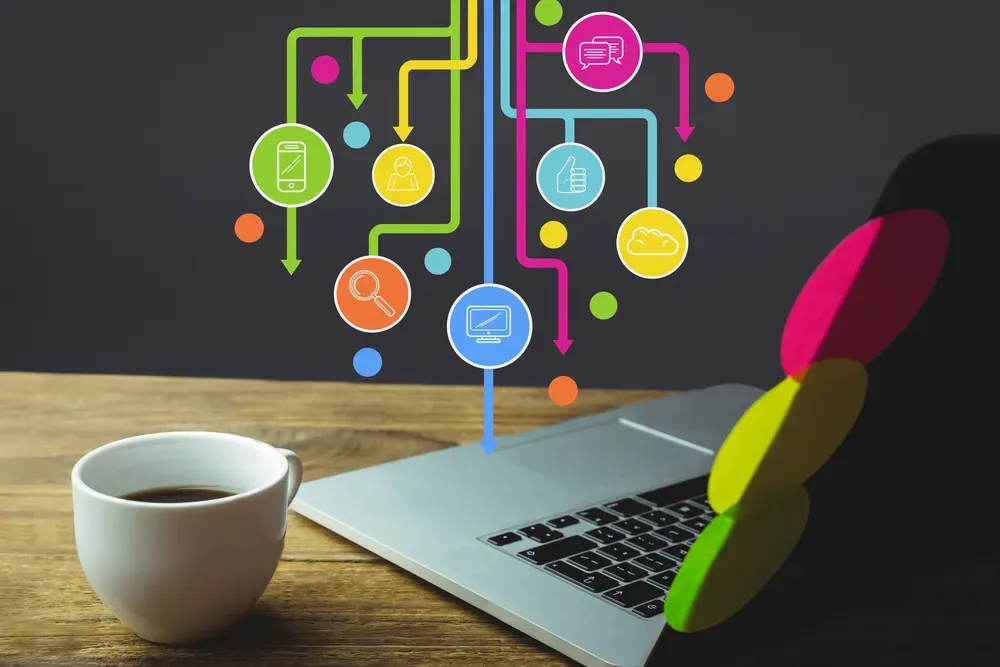 A photo of a desk with a mug and a laptop on it, with colorful infographics appearing from above.
